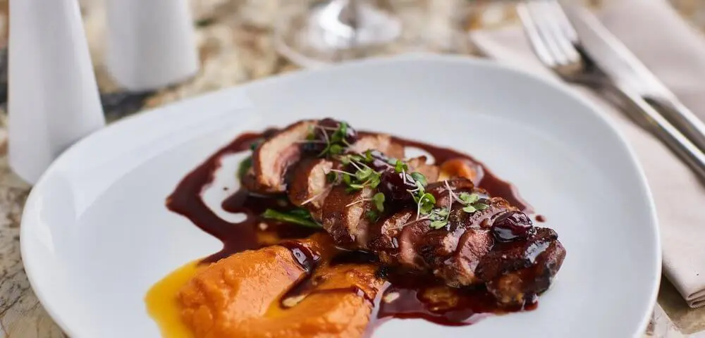 Magret de canard sur un lit de pruneaux et abricots. Sur la photo la viande est accompagnée par une purée de potiron.