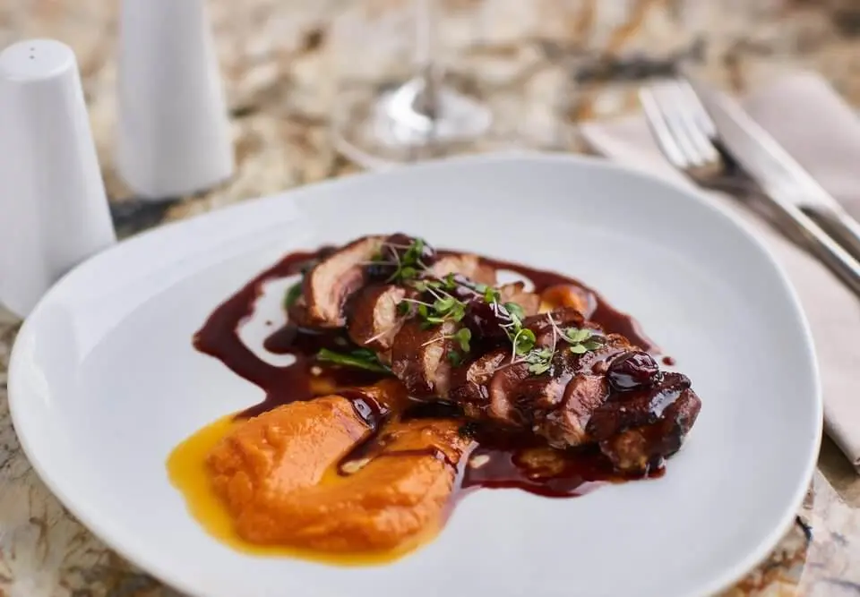 Magret de canard sur un lit de pruneaux et abricots. Sur la photo la viande est accompagnée par une purée de potiron.