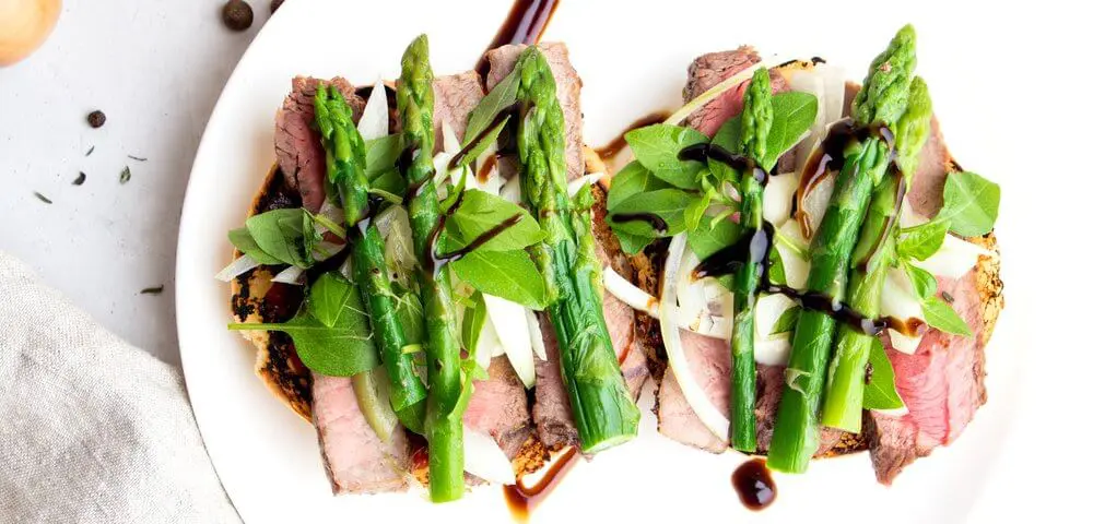 sauté de boeuf sur son lit d'asperges accompagné d'une sauce.