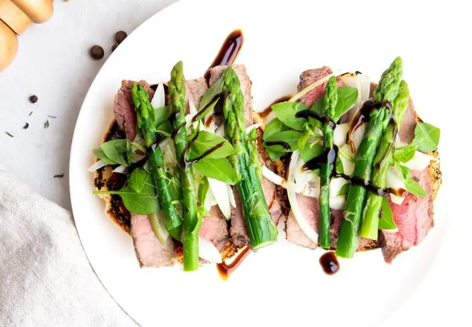 sauté de boeuf sur son lit d'asperges accompagné d'une sauce.